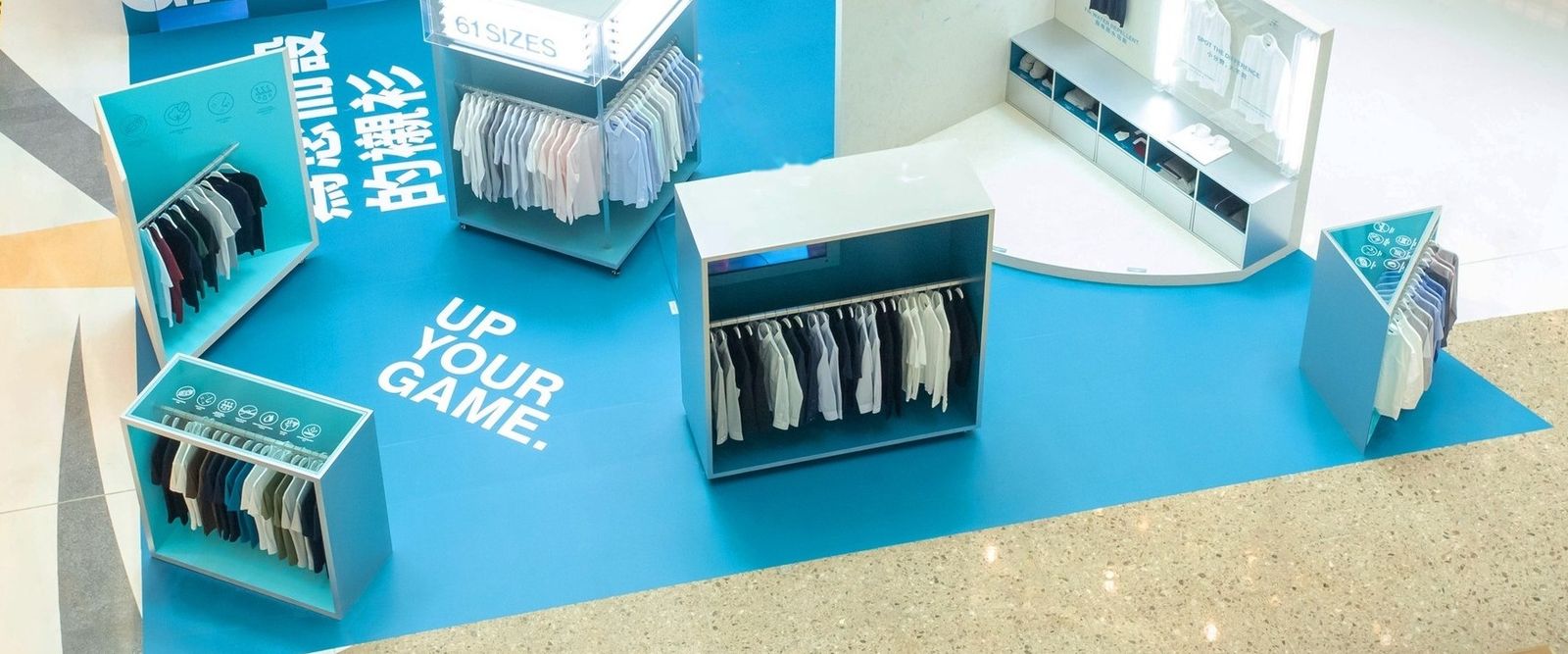DETERMINANT 61 SIZES mall-atrium pop-up seen from above: blue floor graphics and display units