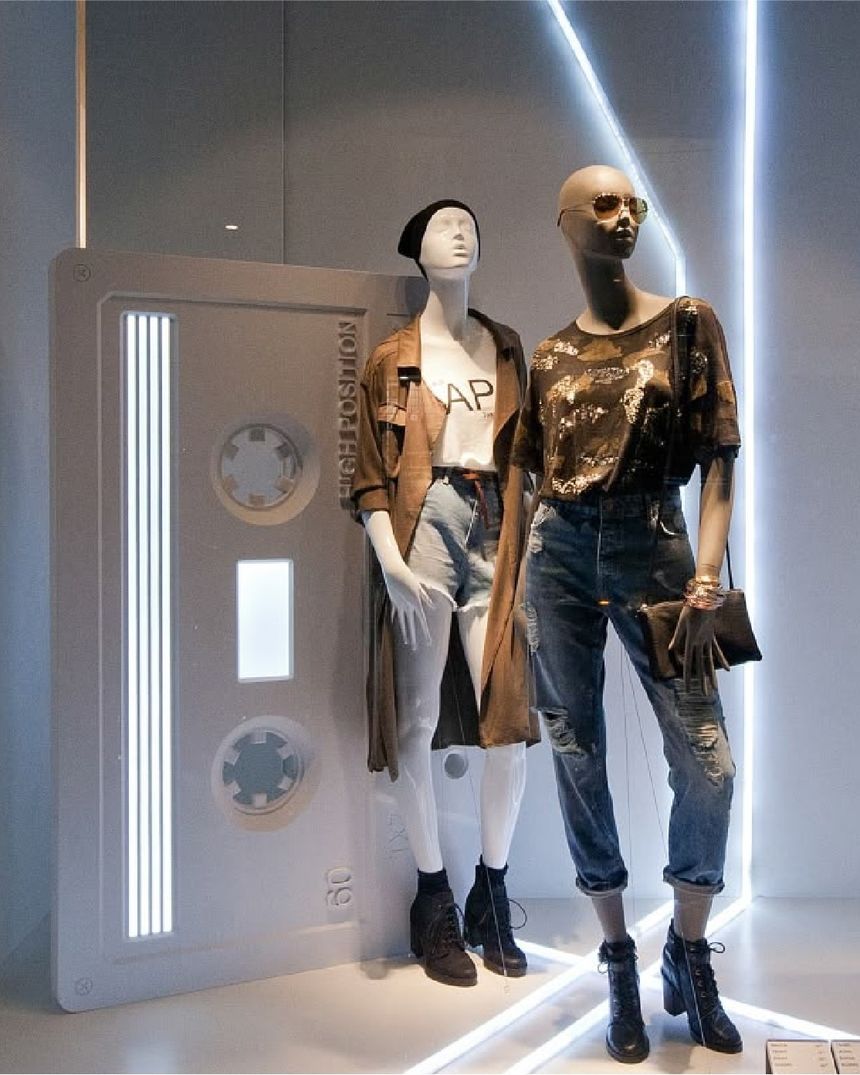 Bershka window: giant cassette-tape prop and LED light lines behind two mannequins